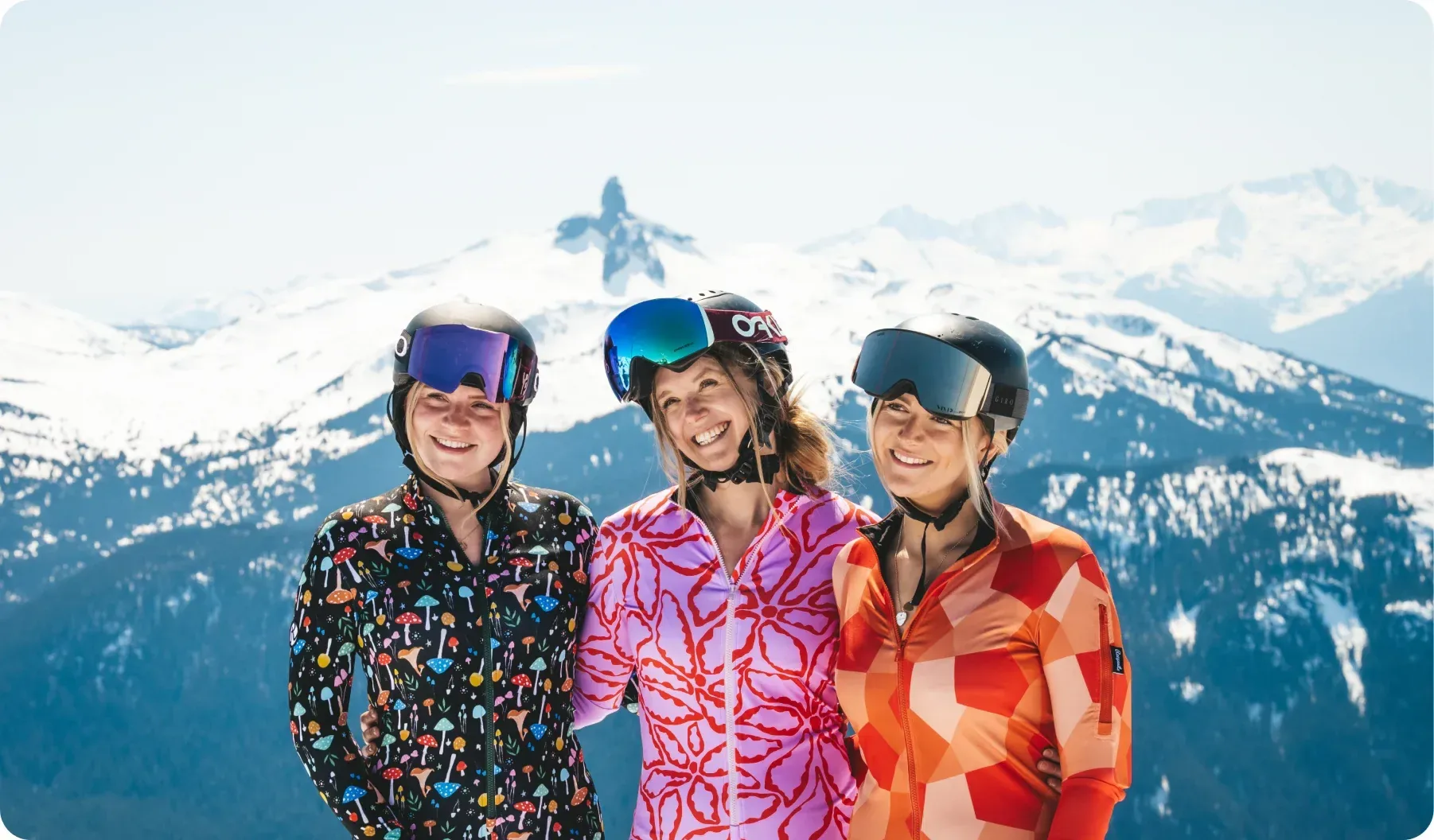Three skiers in Racysuits suits in front of snowy mountains