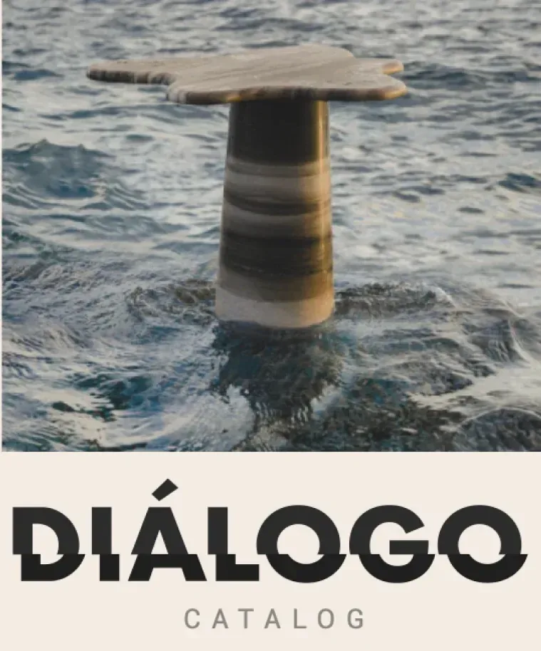 A stone side table standing in water, above the Dialogo catalog cover