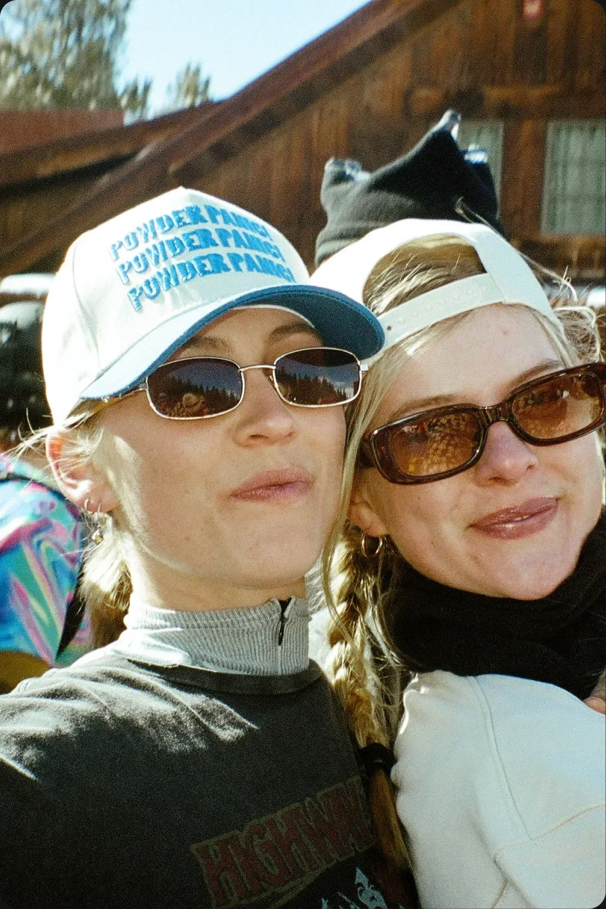 Two friends in Raw & Rebellious caps on the slopes
